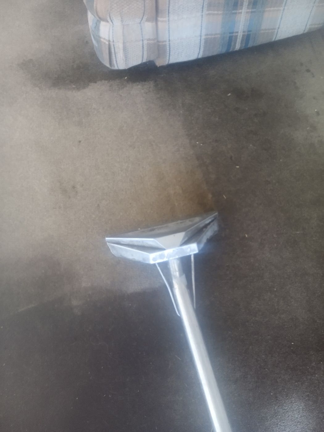 A cleaning wand on dark carpet with a lighter cleaned strip behind it