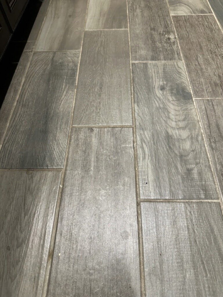 A wood-look tile floor before cleaning