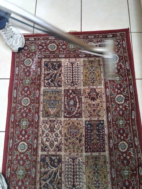 A patterned area rug being cleaned with a wand