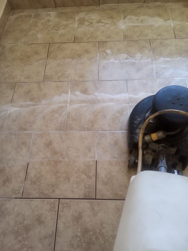 Tile floor being scrubbed with a machine